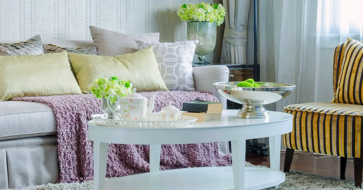 Small living room decorated with white couch and table with pillows and flowers